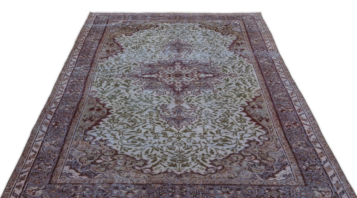 Distressed vintage-style rug with a central medallion and floral motifs in muted burgundy, olive green, and cream.