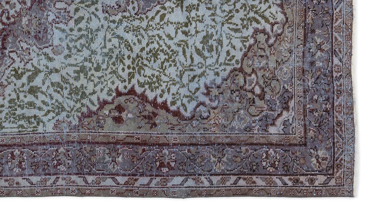 Distressed traditional rug in sage green, brown, and cream with an intricate floral medallion pattern and wide border.
