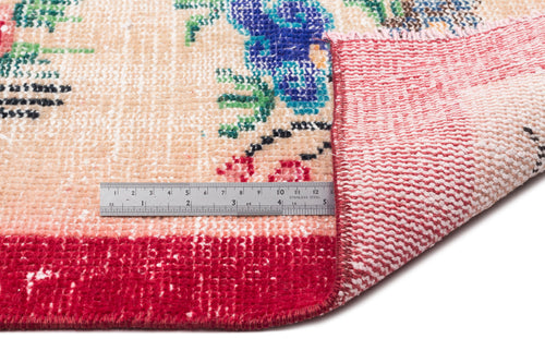 Load image 1 in gallery view. Beige rug with floral pattern in blue, green, and red, showing a folded corner and a metal ruler for scale.