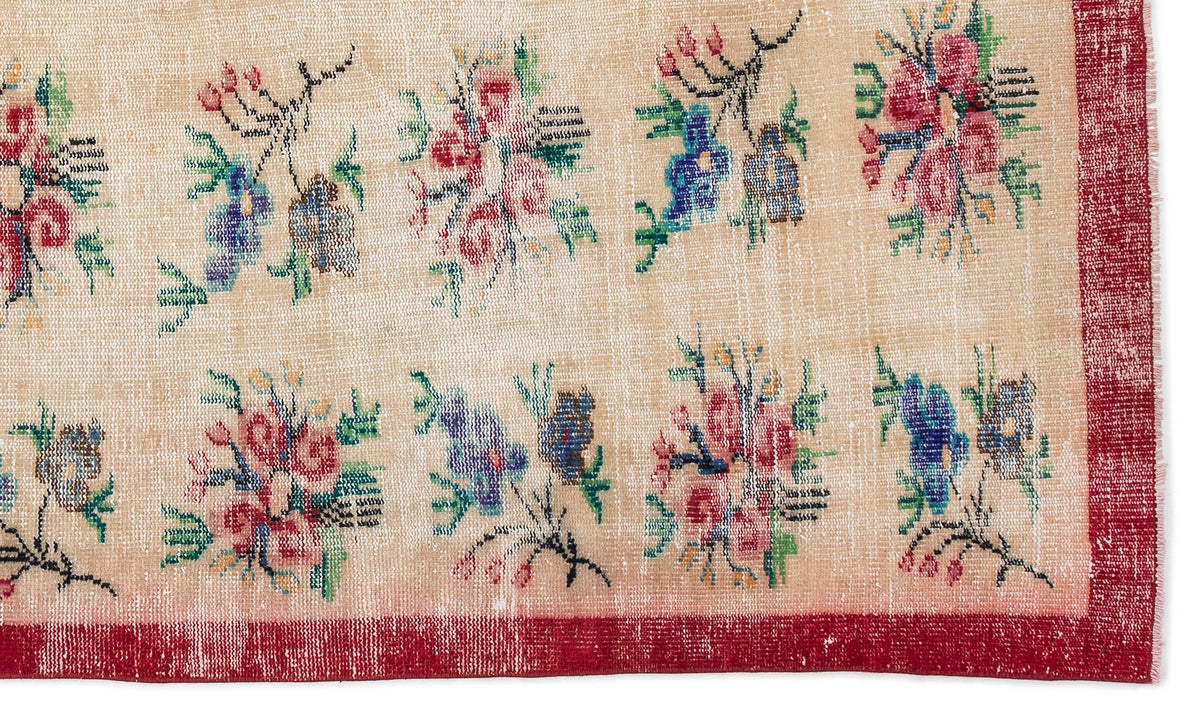 Beige rug with a repeating floral motif in red, blue, and green, featuring a distressed texture and a solid red border.