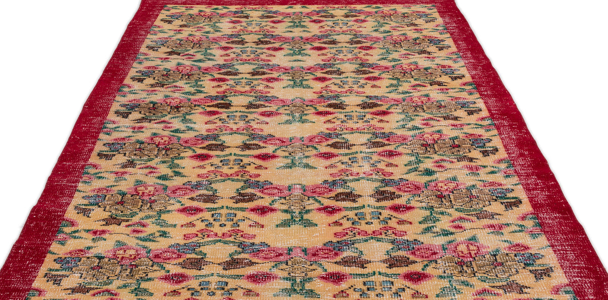 Beige vintage-style rug with a red border and a repeating floral and geometric pattern in red, green, and blue.