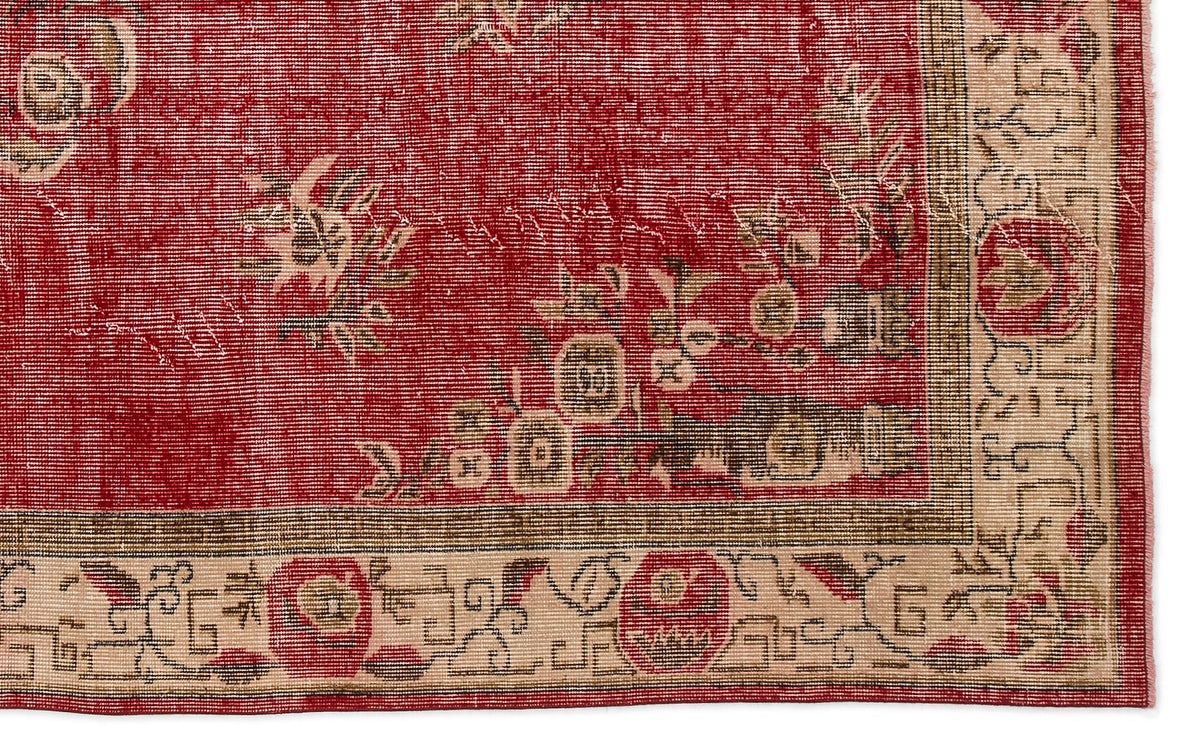 Red rug with a distressed floral pattern and a beige geometric border.