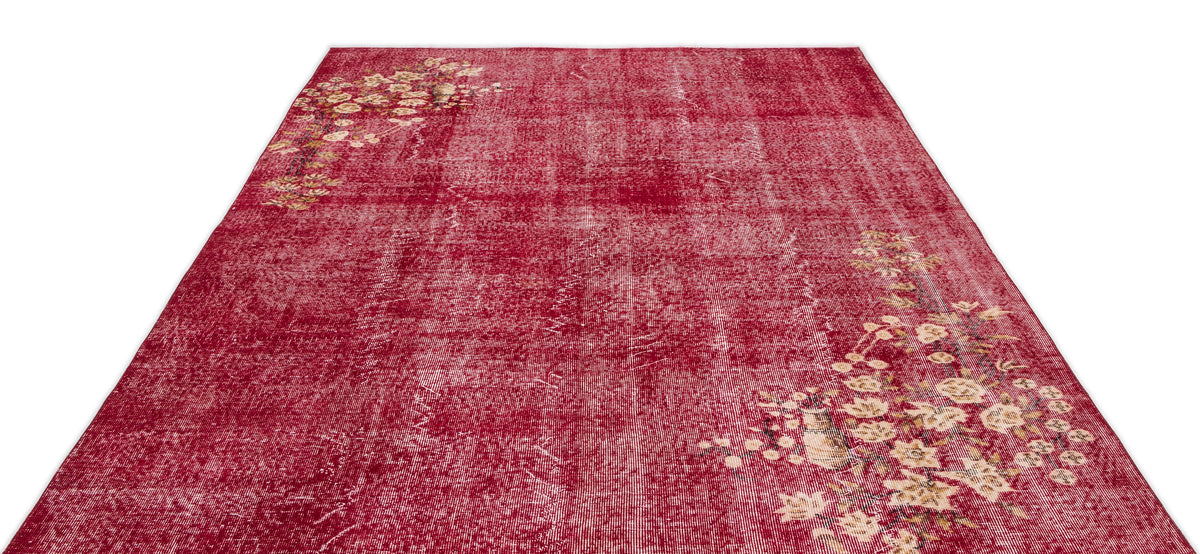 Distressed deep red rug with faded floral corner motifs on a white background.