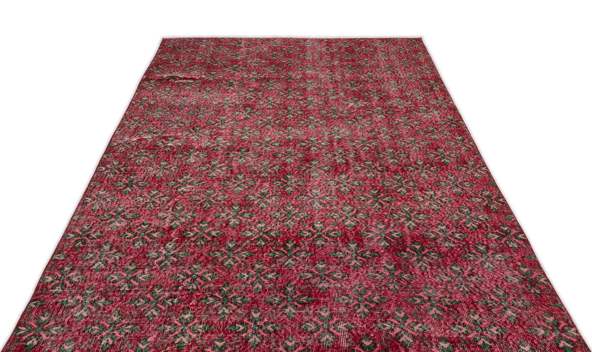 Red vintage-style rug with a repeating green and cream geometric floral pattern on a white background.