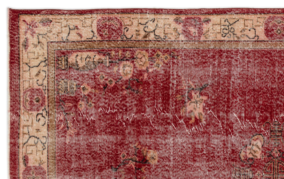 Distressed deep red rug with a beige floral border and traditional geometric motifs.