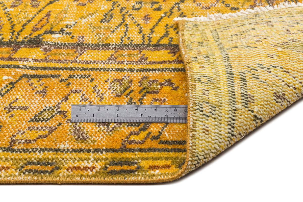 Mustard yellow and brown distressed traditional rug with a floral medallion pattern and white fringe.
