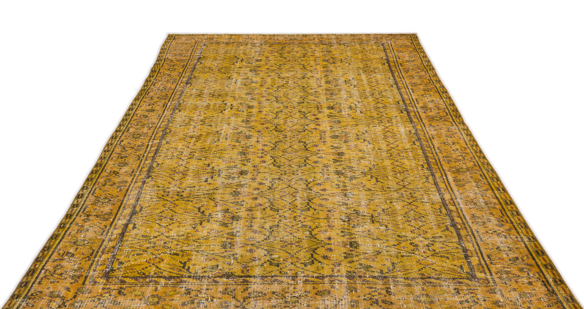 Mustard yellow vintage-style rug with a distressed floral medallion pattern and dark brown border on a white background.