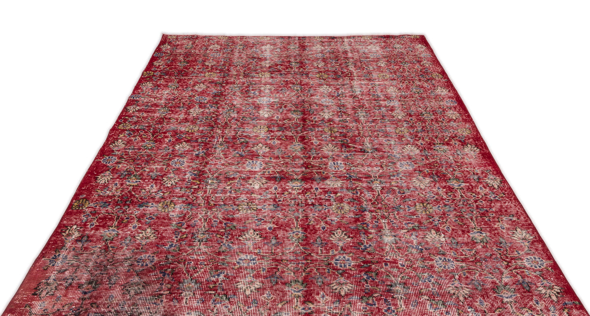 Distressed red rug with a faded floral medallion pattern and hints of blue and yellow on a white background.
