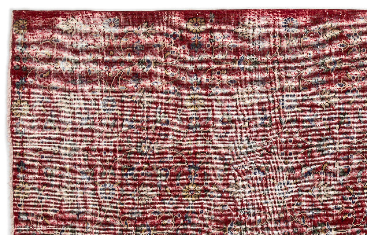 Distressed red rug with a faded floral medallion pattern in cream, blue, and yellow accents.