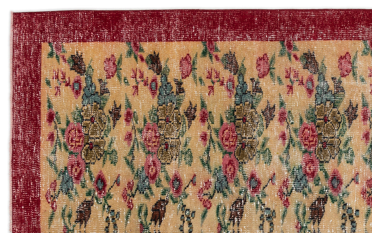 Distressed beige rug with a repeating floral pattern in red, green, and blue, featuring a solid deep red border.