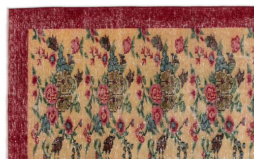 Load image 1 in gallery view. Distressed beige rug with a repeating floral pattern in red, green, and blue, featuring a solid deep red border.