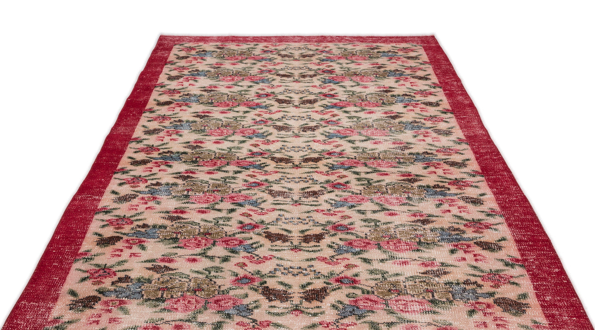 Beige vintage-style rug with a red border and a distressed floral pattern in red, blue, and green.