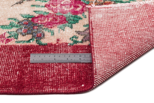 Load image 1 in gallery view. Floral patterned rug with red, green, and cream tones, showing the underside and a metal ruler for scale.