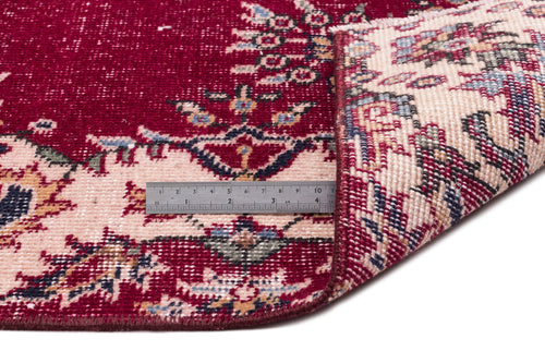 Load image 1 in gallery view. Deep red and cream traditional rug with a floral medallion pattern, shown folded with a metal ruler for scale.