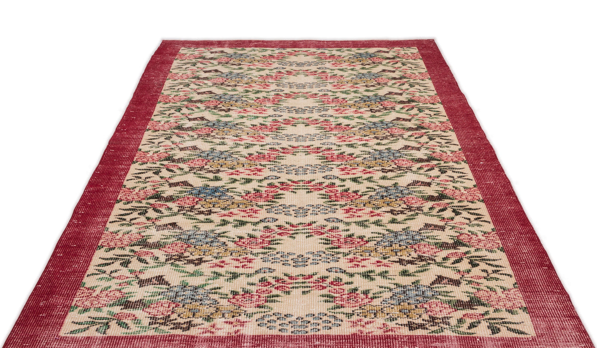 Cream rug with a red border and a repeating floral pattern in red, blue, and green on a white background.