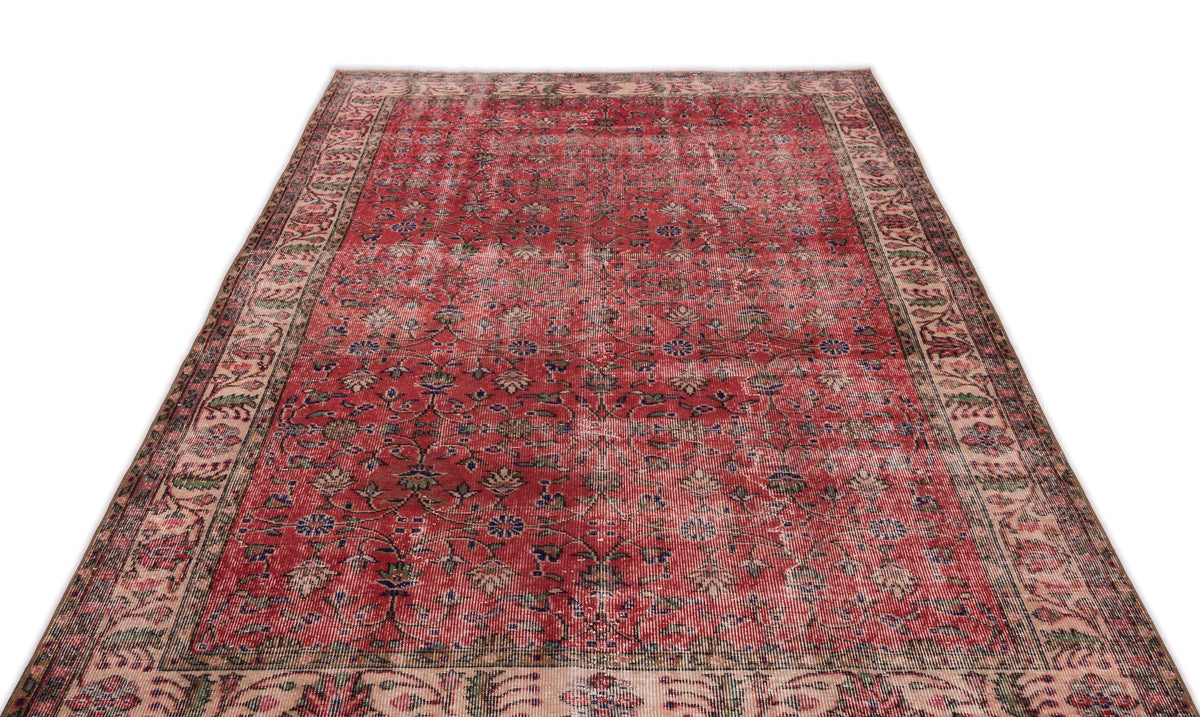 Distressed red Persian-style rug with a floral vine pattern and a wide, intricate border on a white background.
