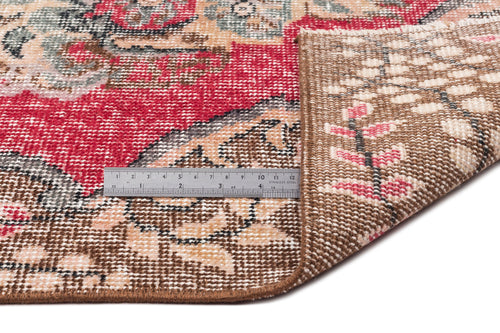 Load image 1 in gallery view. Red, beige, and grey traditional floral rug with a folded corner showing the woven backing and a metal ruler for scale.