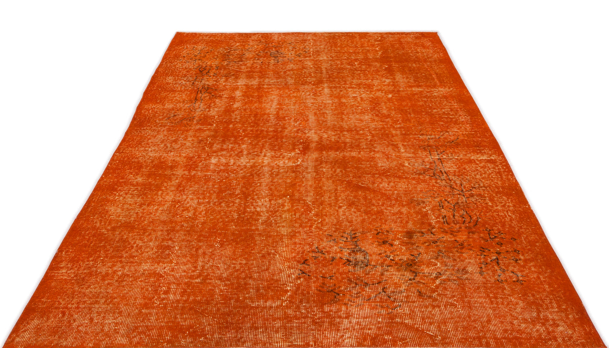 Burnt orange distressed area rug with a faded, traditional floral pattern on a white background.