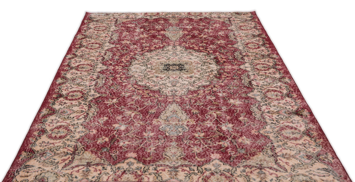 Distressed deep red Persian-style rug with a central floral medallion and intricate cream and charcoal botanical patterns.