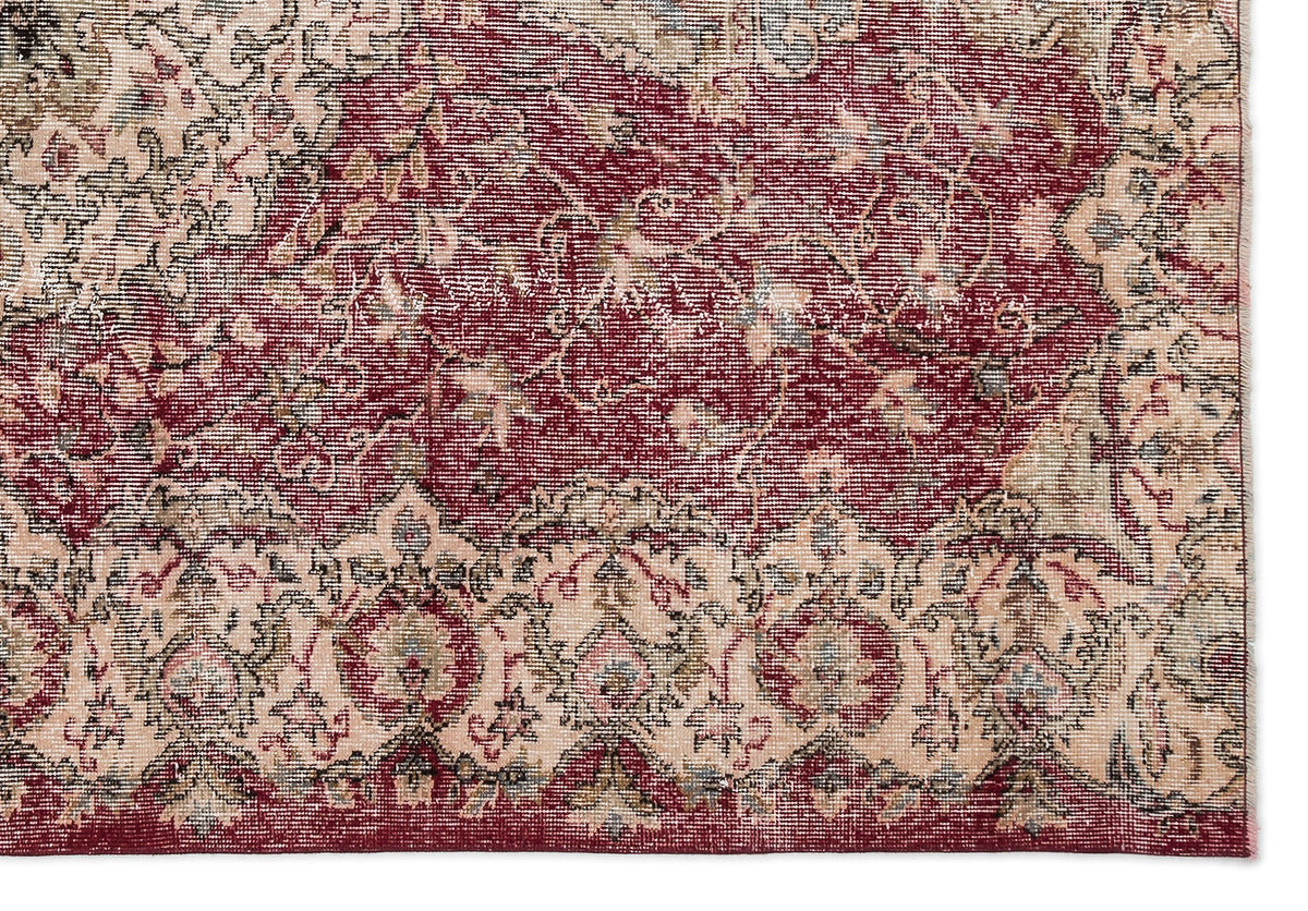 Distressed traditional rug with a deep red field and cream floral medallion border.