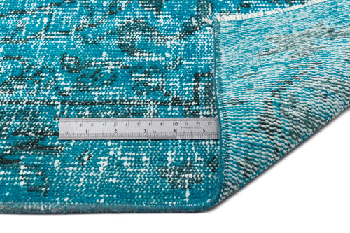 Load image 1 in gallery view. Teal and white distressed medallion rug with a folded corner and a metal ruler for scale on a white background.