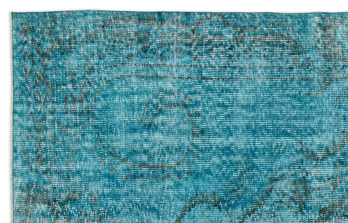 Teal and dark blue distressed rug with a faded, traditional medallion pattern.