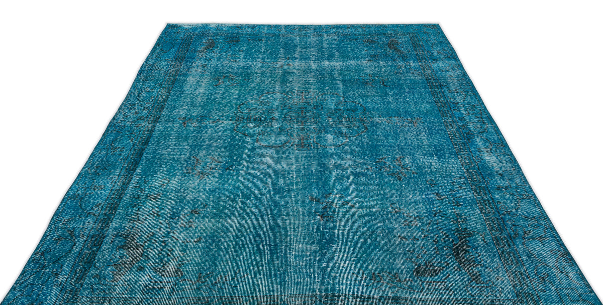 Teal distressed area rug with a faded central medallion and traditional border pattern on a white background.