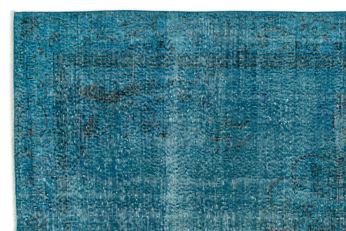 Teal distressed rug with a faded black traditional border and floral motif.