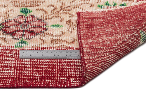 Load image 1 in gallery view. Beige and red vintage-style rug with a floral medallion pattern, shown folded with a metal ruler for scale.