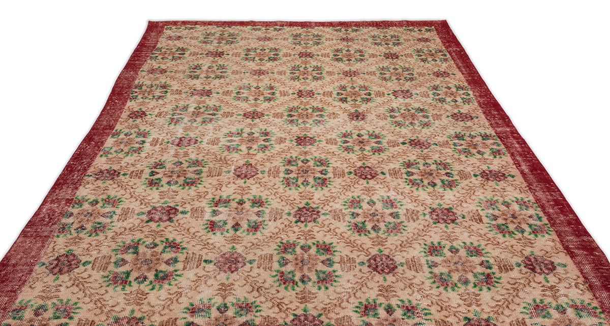 Beige rug with a red border and repeating floral medallion pattern in red and green on a white background.