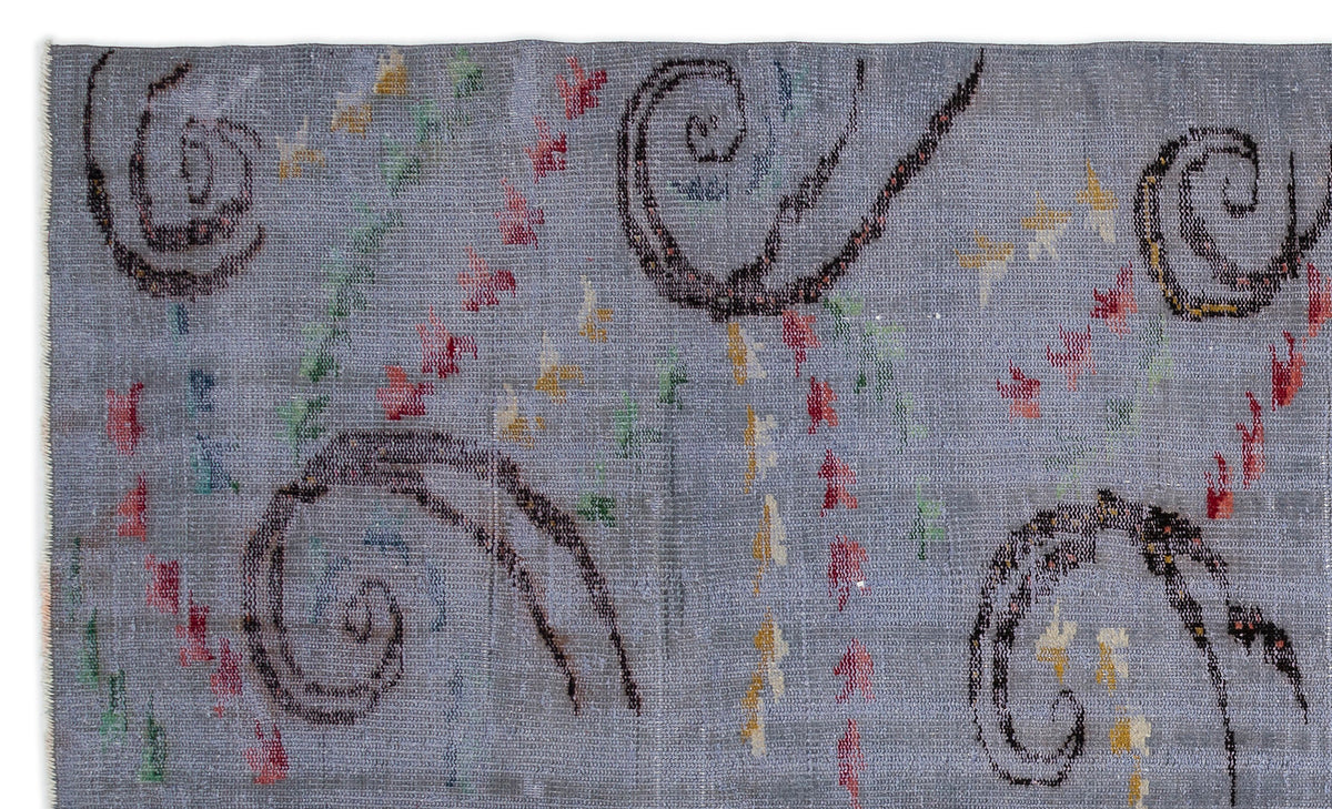 Grey rug with dark brown spiral motifs and scattered red, yellow, and green abstract accents.