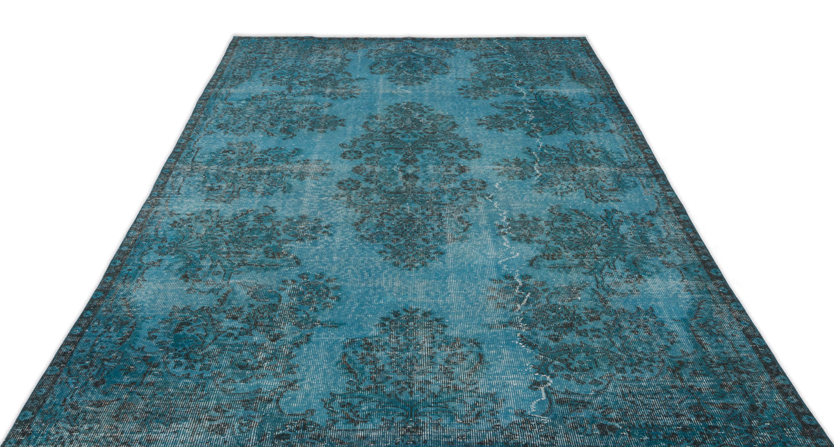 Distressed turquoise and charcoal rug with a repeating traditional floral medallion pattern.