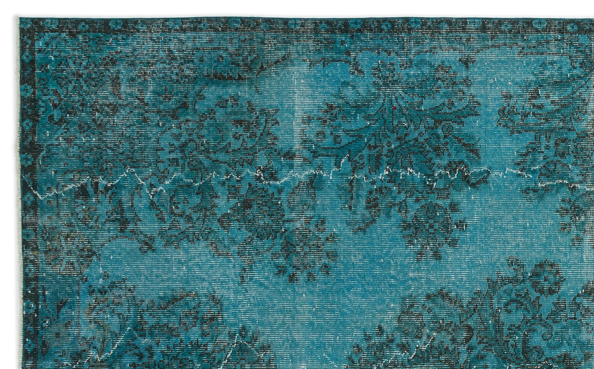 Teal and black distressed rug with a traditional floral medallion pattern and a dark border.