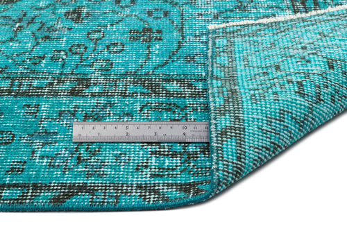 Load image 1 in gallery view. Turquoise and black distressed medallion rug with a folded corner and a metal ruler for scale on a white background.