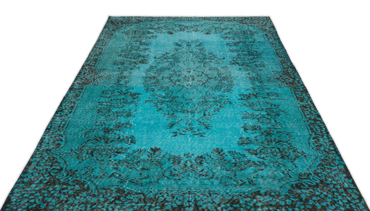 Turquoise and black distressed rug with a traditional floral medallion pattern on a white background.