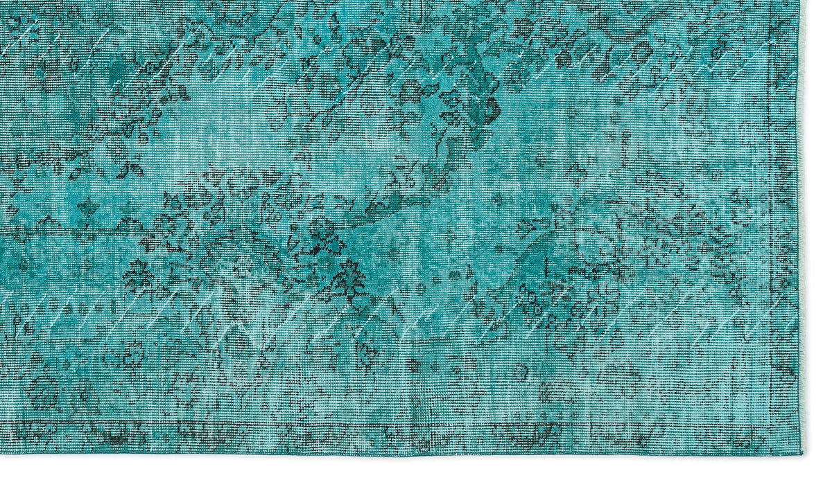Teal rug with a distressed, faded floral medallion pattern and a visible woven texture.