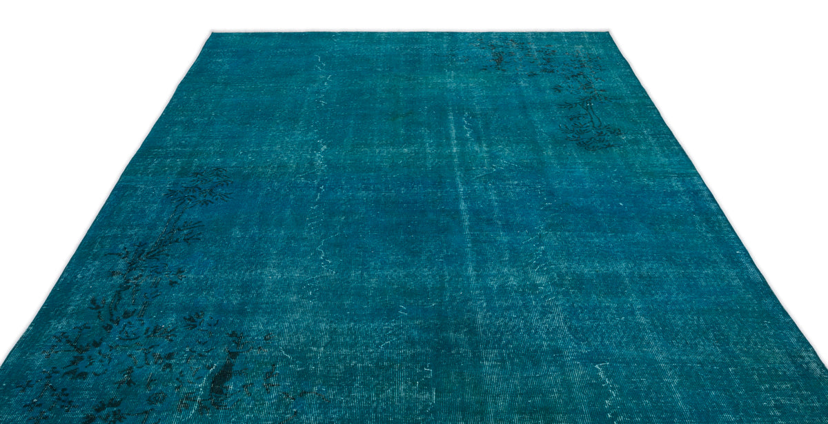 Teal distressed area rug with a faded, dark floral medallion pattern on a white background.