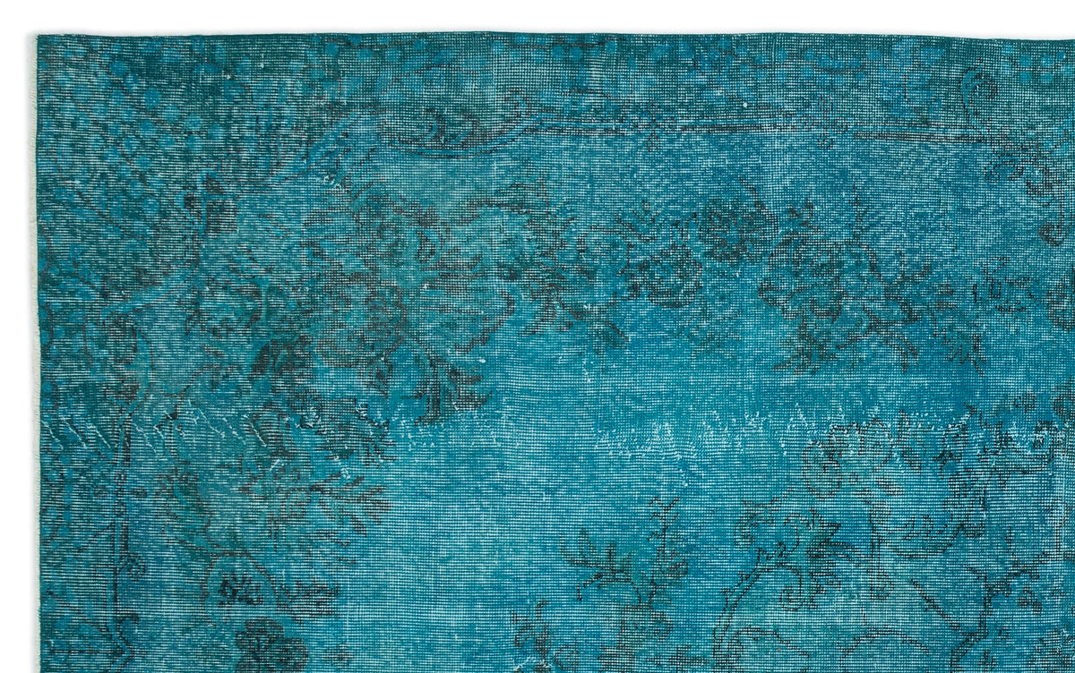 Teal distressed rug with a faded black traditional floral pattern.