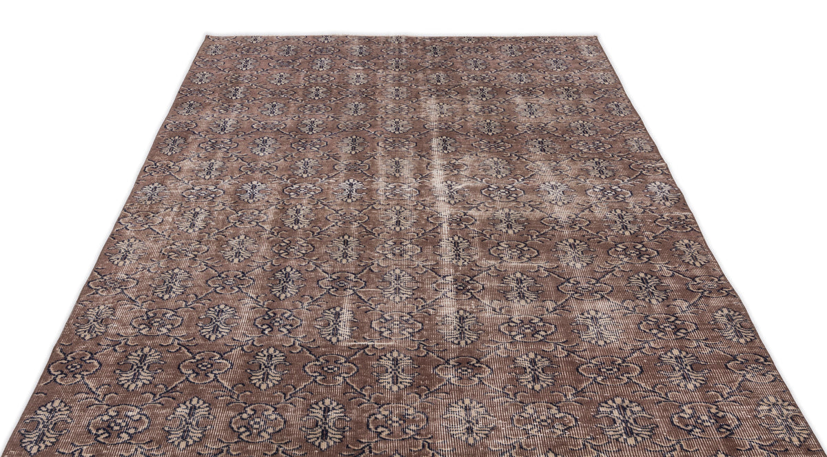 Brown and dark blue distressed rug with an all-over repeating floral medallion pattern on a white background.