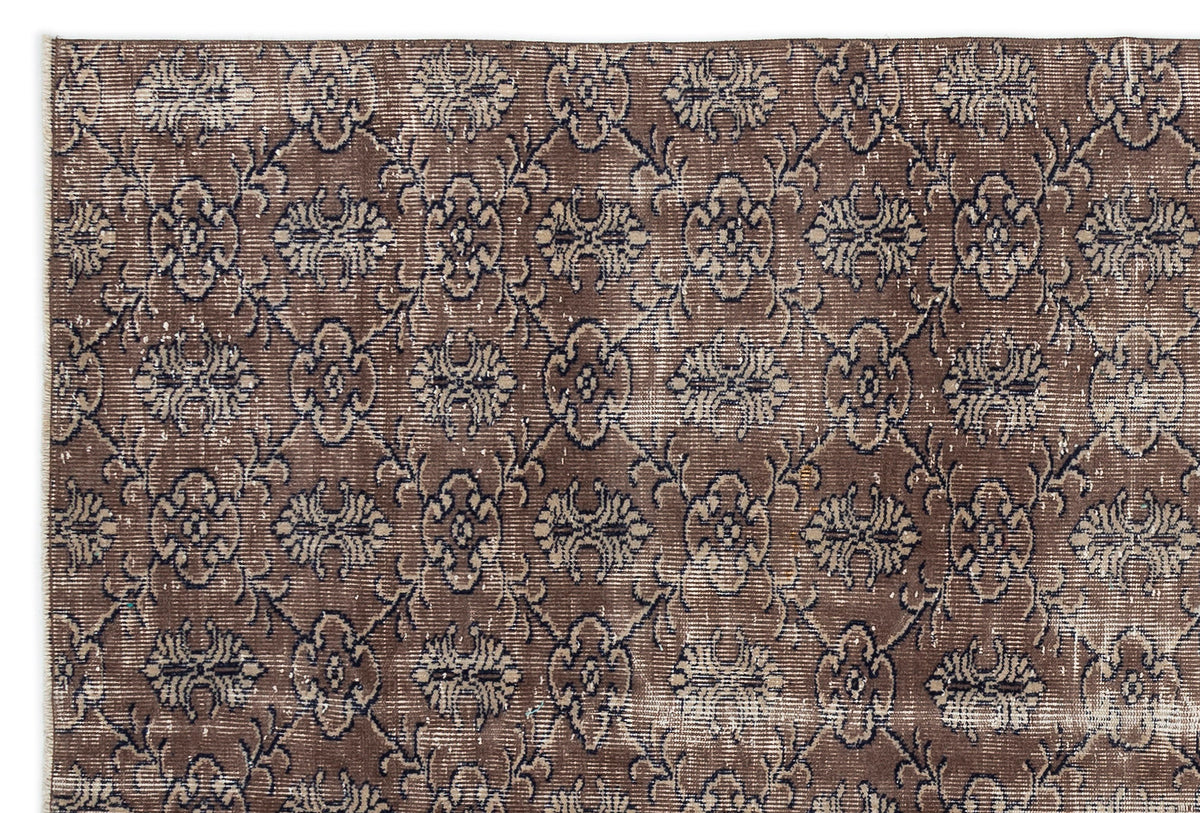 Brown and charcoal distressed rug with a repeating floral medallion pattern in a lattice grid.