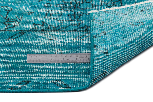 Load image 1 in gallery view. Teal and black distressed patterned rug with a folded corner and a metal ruler for scale on a white background.