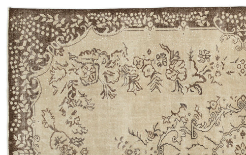 Load image 1 in gallery view. A close-up of the Tiduex Vintage Medallion Rug (6'3" x 9'11") shows its beige background and ornate brown floral and vine border, featuring detailed motifs inspired by classic Anatolian rug craftsmanship.