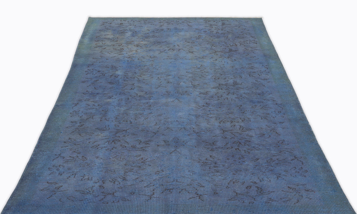 Deep blue vintage-style rug with a faint, distressed floral pattern on a white background.