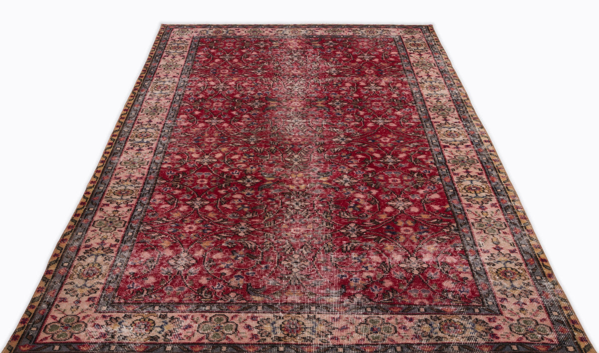 Deep red traditional rug with a distressed floral medallion pattern and a multi-colored border on a white background.