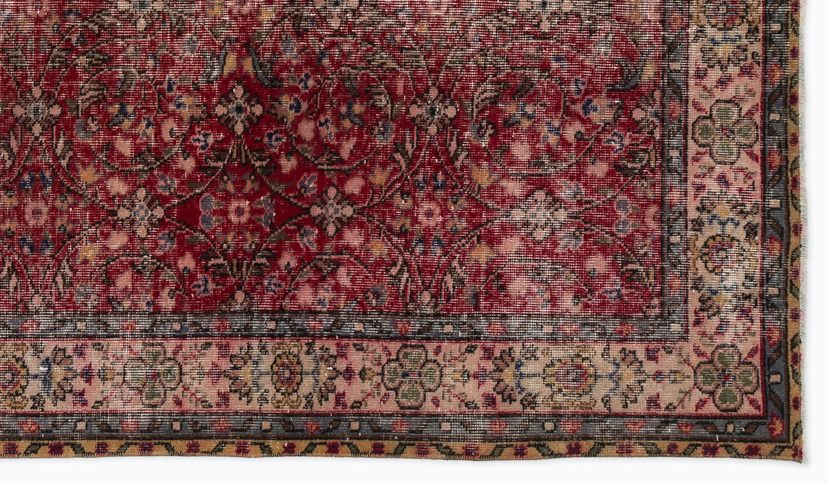 Deep red traditional rug with a distressed floral pattern and a beige border featuring intricate geometric motifs.