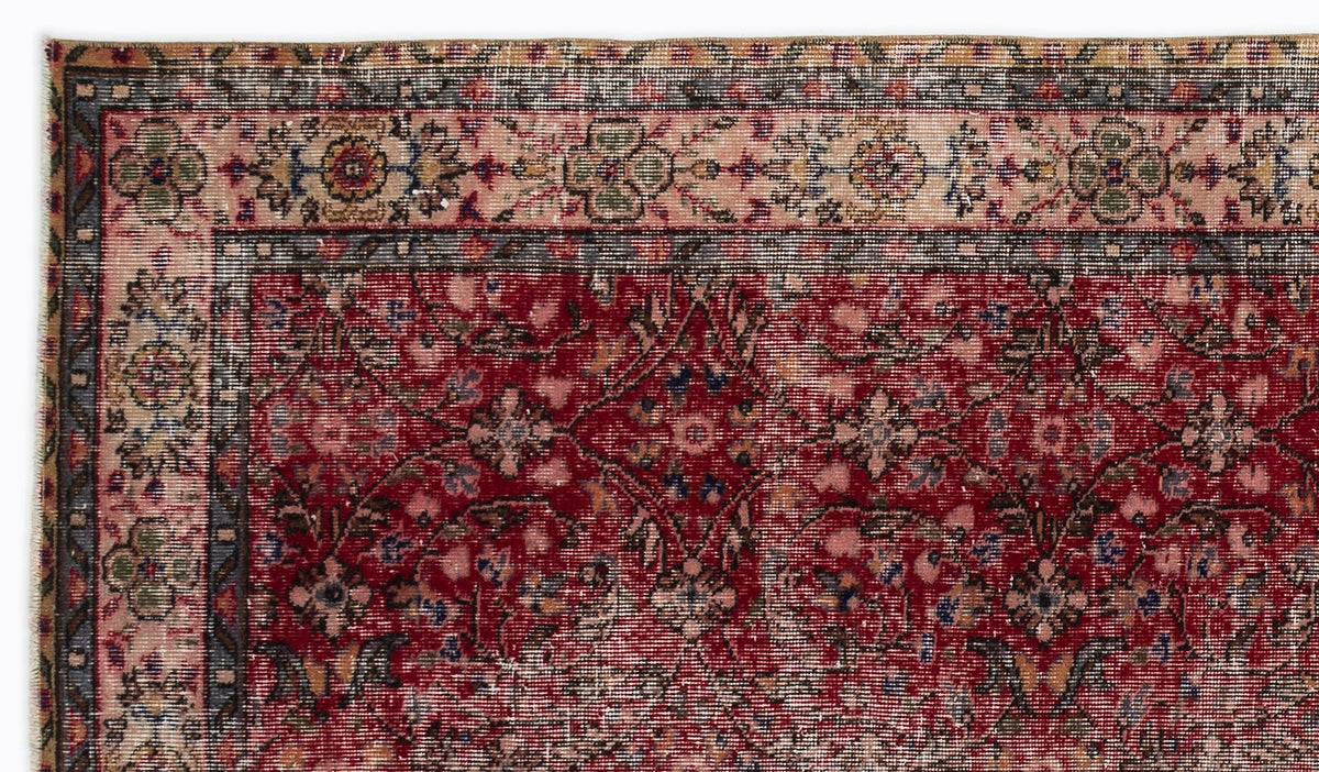 Deep red traditional rug with a floral medallion pattern and a multi-colored decorative border.