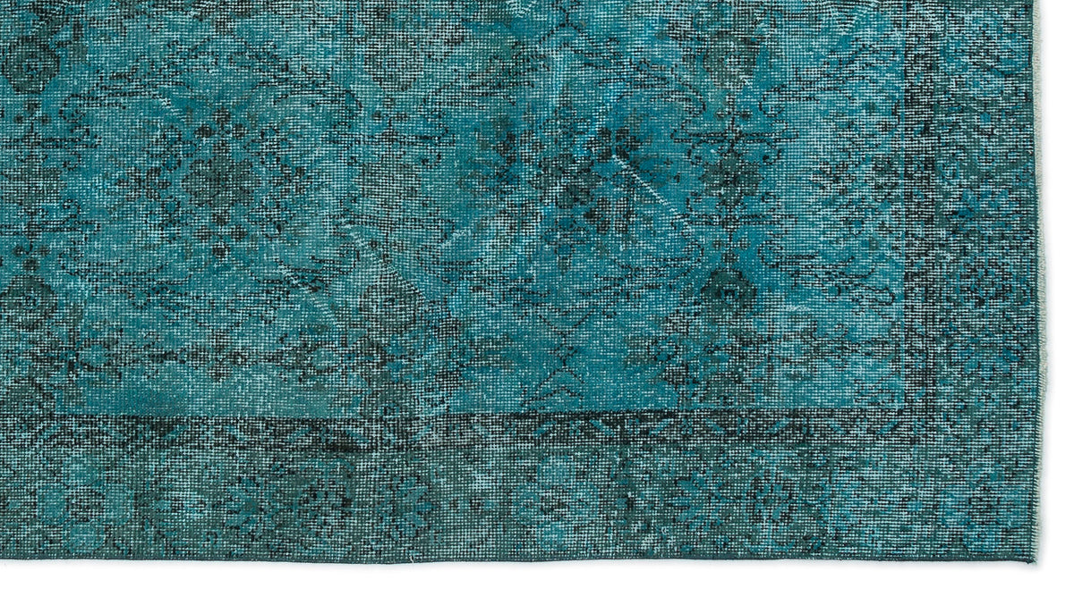 Teal and black distressed rug with a faded traditional medallion pattern and a dark border.