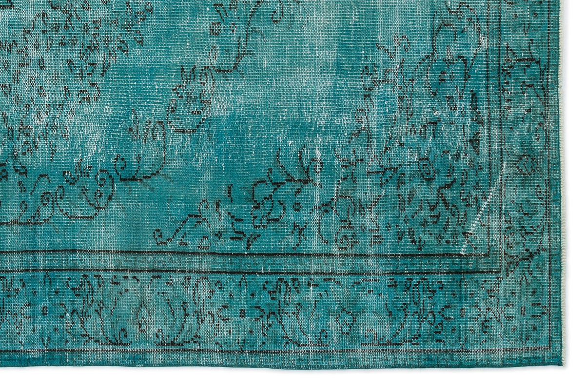 Teal distressed rug with a black floral medallion pattern and a bordered edge on a white background.