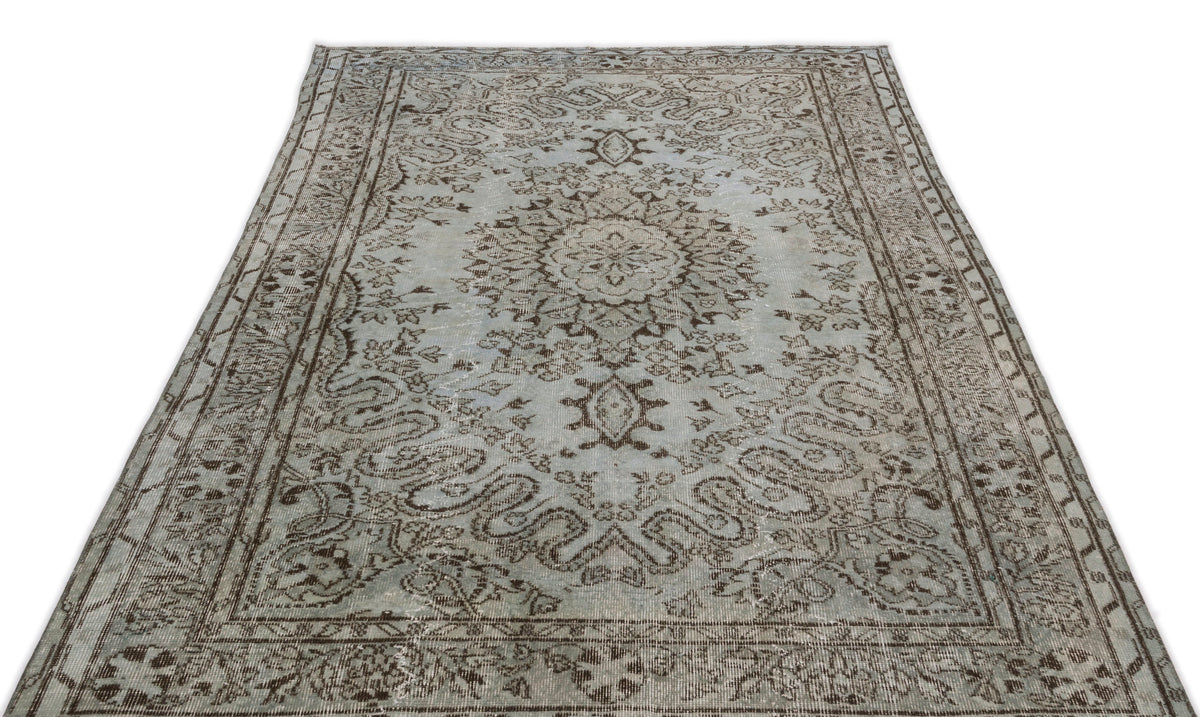 Light blue and brown distressed traditional rug with a central floral medallion and ornate border pattern.