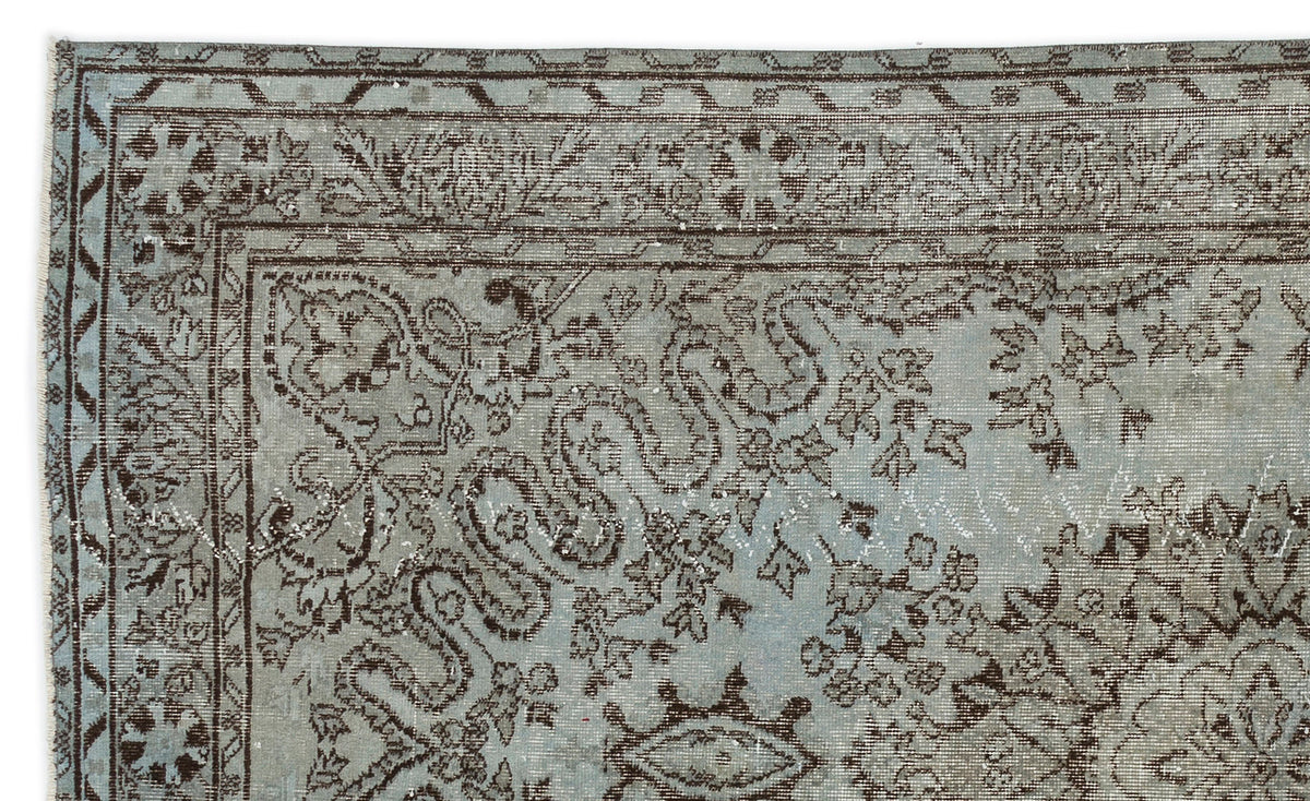 Light blue and dark brown distressed rug with a traditional floral and vine border pattern.